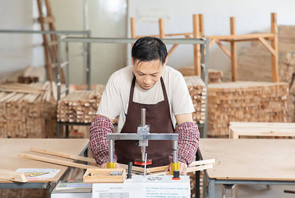 A worker is handcrafting a wood stretcher.